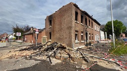 Das abgebrannte Wohnhaus in Grevenbroich. Das Haus hat kein Dach mehr. Vor dem Haus liegen Holzbalken.