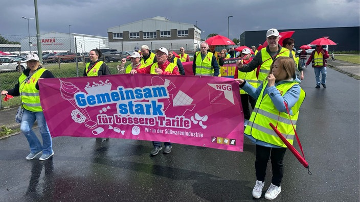 streikende Menschen halten ein Banner mit Aufschrift "Gemeinsam stark für bessere Tarife. Wir in der Süßwarenindustrie" 