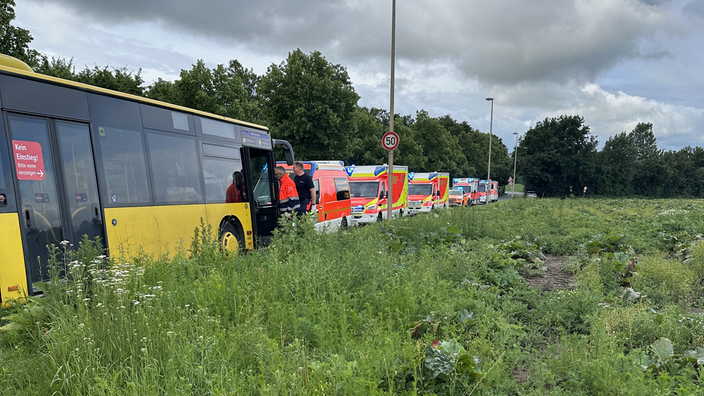 Der gelbe Schulbus steht am Straßenrand. Daneben sind einige Fahrzeuge des Rettungsdienstes zu sehen.