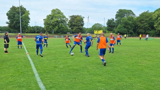 Zwei Mannschaften spielen auf einem Rasenplatz Fußball