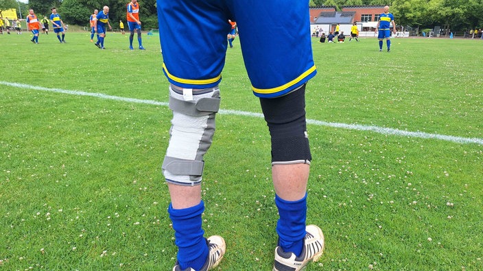 Zu sehen ist ein Fußballspieler mit Kniemanschetten