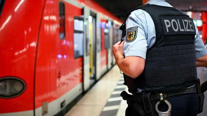 Ein Polizist steht in Montur an einem S-Bahn-Gleis.