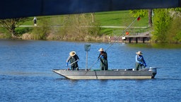 Drei Fischer sind auf einem Boot auf dem Aasee unterwegs