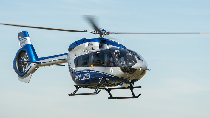 Ein Polizeihubschrauber mit Pilot, der sich in der Luft befindet.