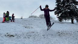 Kind springt über selbstgebaute Schanze