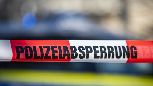 rot, weiß gestreiftes Flatterband auf dem steht: "Polizeiabsperrung"