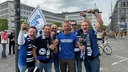 Eine Gruppe Männer jubelt und reißt die Arme hoch.