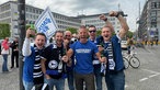 Eine Gruppe Männer jubelt und reißt die Arme hoch.
