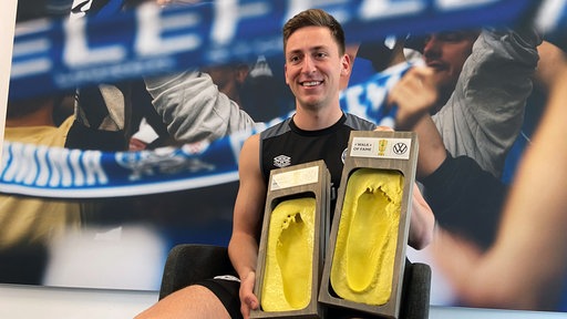 Arminia-Spieler Marius Wörl bekommt eingegipste Füße: Für den DFB "Walk of Fame" in Berlin".