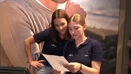 Zwei Azubis lesen einen Brief ihrer Ausbildungsleiterin