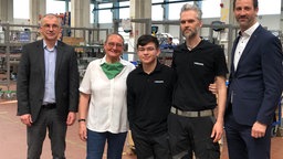 Azubi und Belegschaftsmitglieder in Maschinenhalle