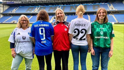 Fünf Frauen im Stadion, die Fußballtrikots tragen.