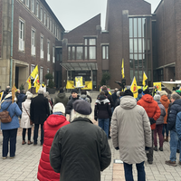 Eine Menschenmenge von hinten, einige halten gelbe Banner in die Luft