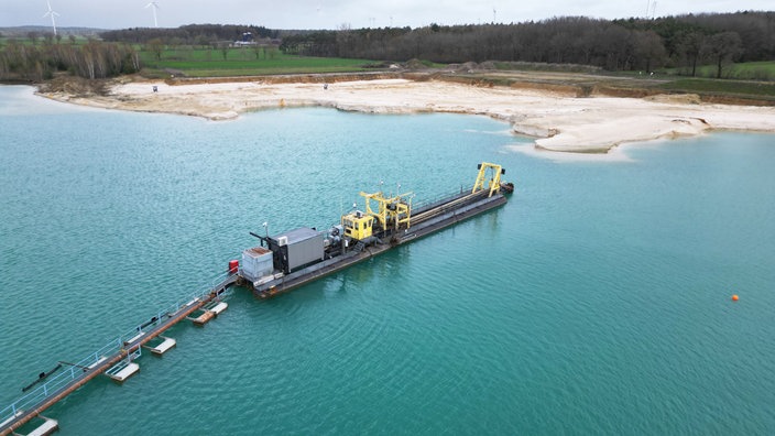 Ds Baggerschiff auf dem Gewinnungssee, im Hintergrund Quarzsand
