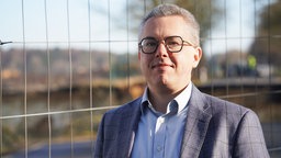 Ein Mann steht vor einem Bauzaun