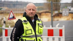 Mann in Warnweste steht vor Absperrung