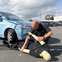 Mann und Crashtest-Dummy vor einem Auto