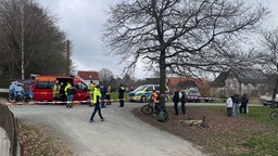 Rettungsdienst und Polizei stehen hinter einer Absperrung, Schaulustige davor.