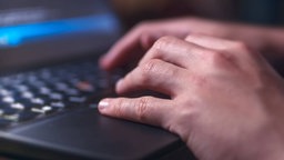 Hände tippen auf der Tastator eines Laptops. 