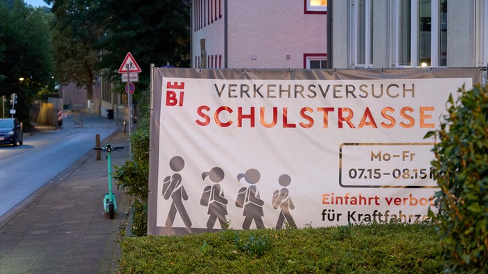 Ein Banner mit der Aufschrit "Verkehrsversuch Schulstraße"