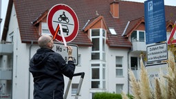 Ein mitarbeiter der Stadt entfernt einen Aufkleber vom "Durchfahrt verboten"-Schild