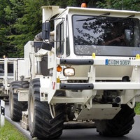 Mehrere Vibro-Trucks, die hintereinander auf einer Landstraße fahren.