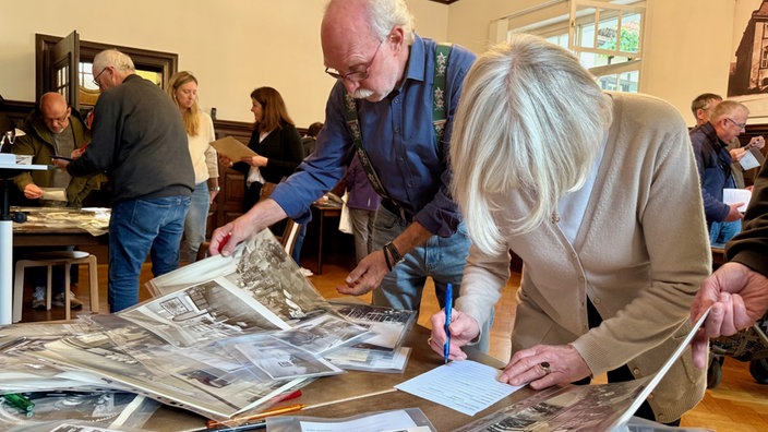 Mann und Frau stehen am Tisch mit Fotos.