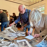 Mann und Frau stehen am Tisch mit Fotos.