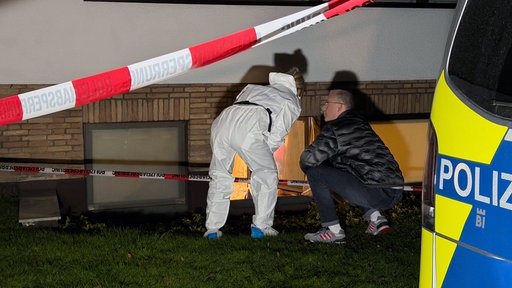 Zwei Polizeibeamte stehen vor dem Fenster des Kellers, wo die Leiche gefunden wurde.