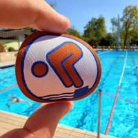 Ein Bronze-Schwimmabzeichen mit dem Freibad Verl im Hintergrund
