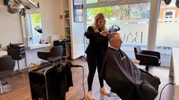 Friseurin schneidet Mann die Haare