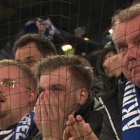 Drei Männer mit Arminia Bielefeld-Schal sitzen am Spielfeldrand und betrachten das Spiel