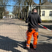 Ein Mann steht vor einem Bauzaun, der einen Bereich absperrt 