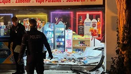 Polizisten vor dem zerstörten Schaufenster.