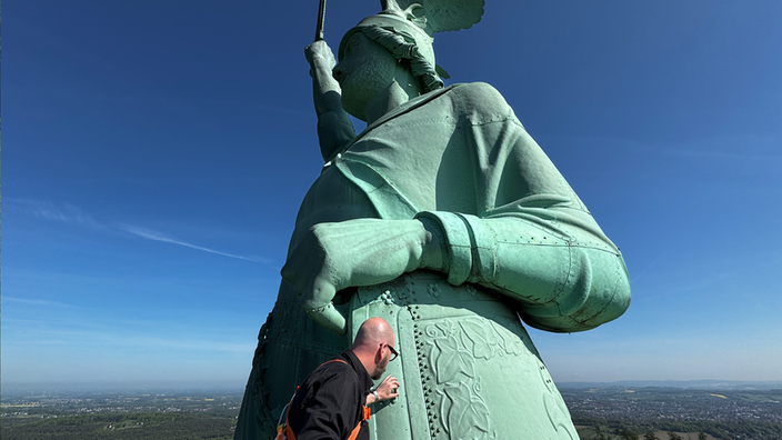 Ein Mann tastet das Hermannsdenkmal ab