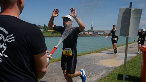 Feuerwehr Münster kühlt einen Triathlet mit Wasser ab