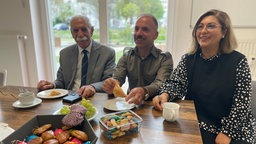 Die Mitglieder des Deutsch-Ezidischen Kulturvereins mit Kaffetassen und Gebäck am Tisch 