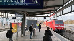 Menschen stehen am Bahnsteig in Mühlheim und ein DB Zug steht am Gleis 2.