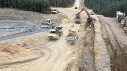 Eine große Baustelle im Wald mit Baggern, Muldenkippern und anderen Fahrzeugen