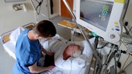 Ein Krankenpfleger kümmert sich in einem Krankenhaus um einen älteren Patienten