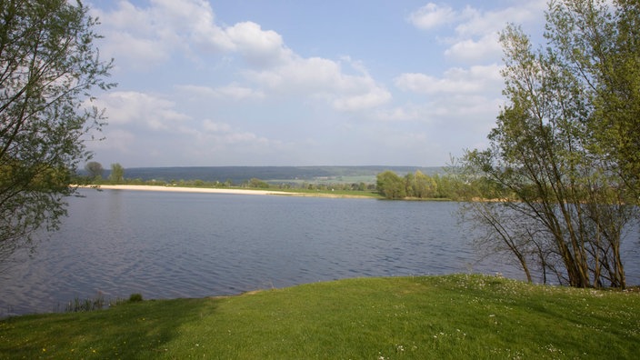 Blick von einem grünen Ufer über den Godelheimer See bei Höxter