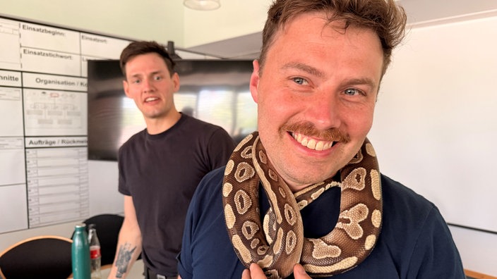 ein Feuerwehrmann hat sich eine Python um den Hals gelegt