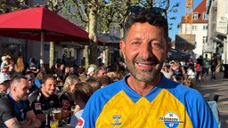 Ein Mann im gelbblauen Trikot schaut in die Kamera