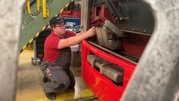 ein Mann der an einer Bahn in einer Werkstatt arbeitet