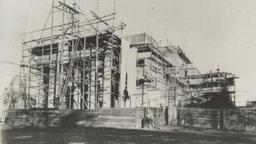 Das Foto ist schwarz, weiß. Wir sehen das Landestheater von außen, eingekleidet mit Baugerüsten. Das Dach fehlt, die markanten Säulen haben den Brand überlebt.
