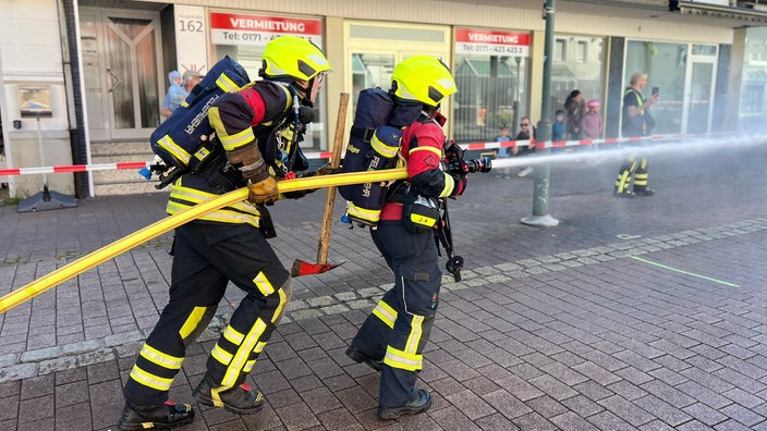 Feuerwehrleute mit einem Schlauch üben in der Innenstadt