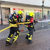 Feuerwehrleute mit einem Schlauch üben in der Innenstadt
