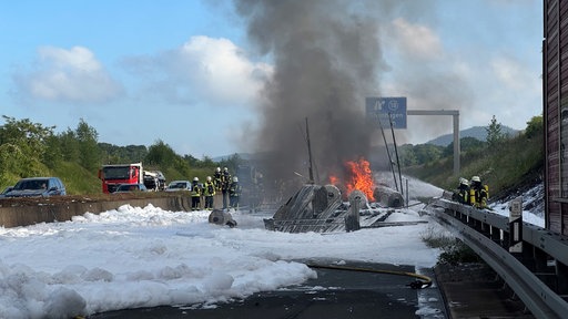 Überreste eines brennenden LKWs in einem Meer aus Löschschaum