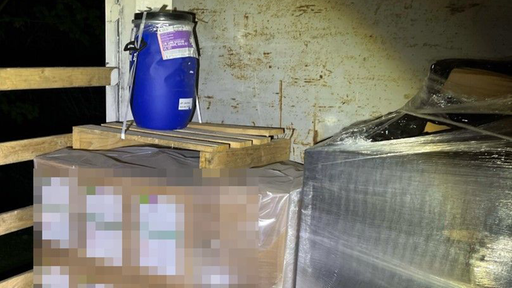 Kartons und ein blaues Fass mit giftiger Ladung im Innenraum eines LKWs