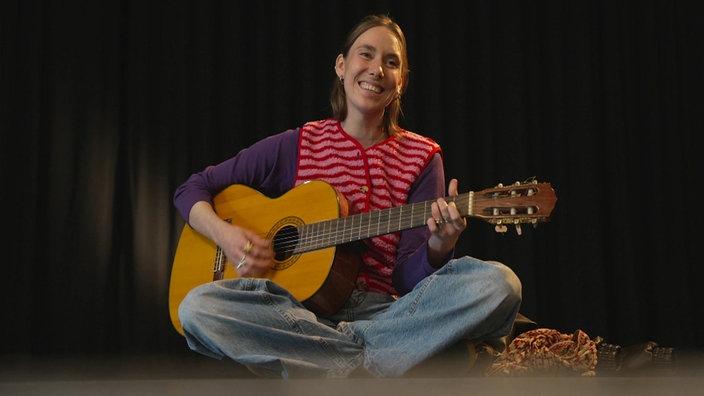 Malou Lovis spielt Gitarre.